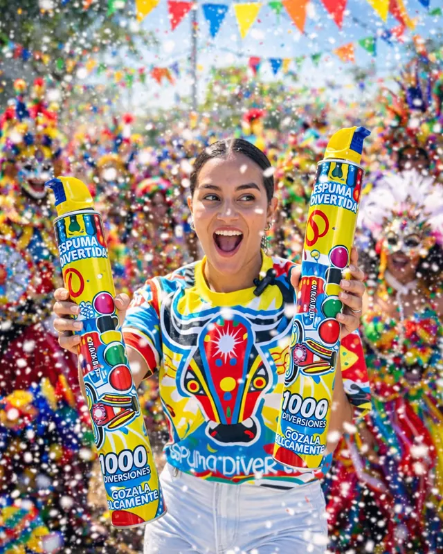 Joven feliz con dos latas de Espuma Torito en pleno carnaval, entre confeti y banderines